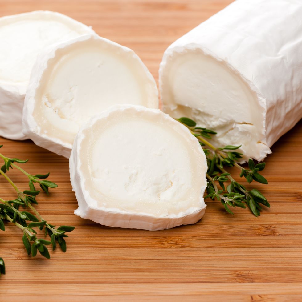 slices of goat cheese with fresh thyme on a bamboo cutting board