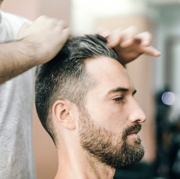 bearded man receiving haircut in the barbershop