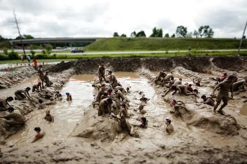participants climb through mud at a tough mudder event near toronto, canada