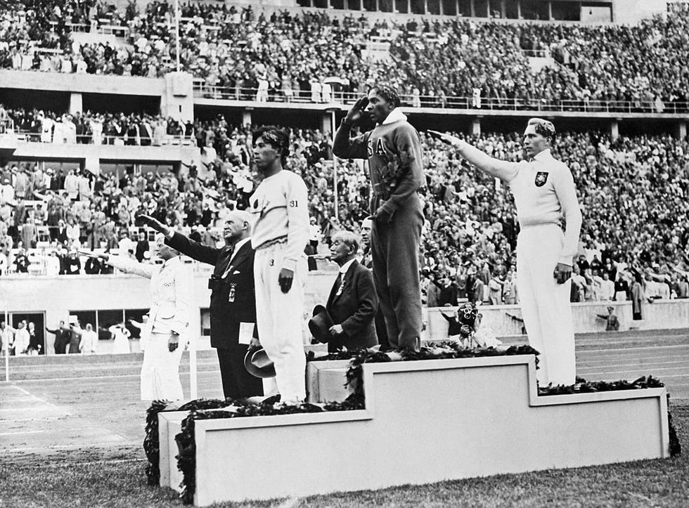 the gold, silver and bronze medal winners in the long jump competition salute from the victory stand at the 1936 summer olympics in berlin from left, japans naoto tajima bronze, american jesse owens gold who set an olympic record in the event and offers an american style salute with his hand to his forehead, and germanys luz long silver giving a nazi salute with his arm extended out august 8, 1936