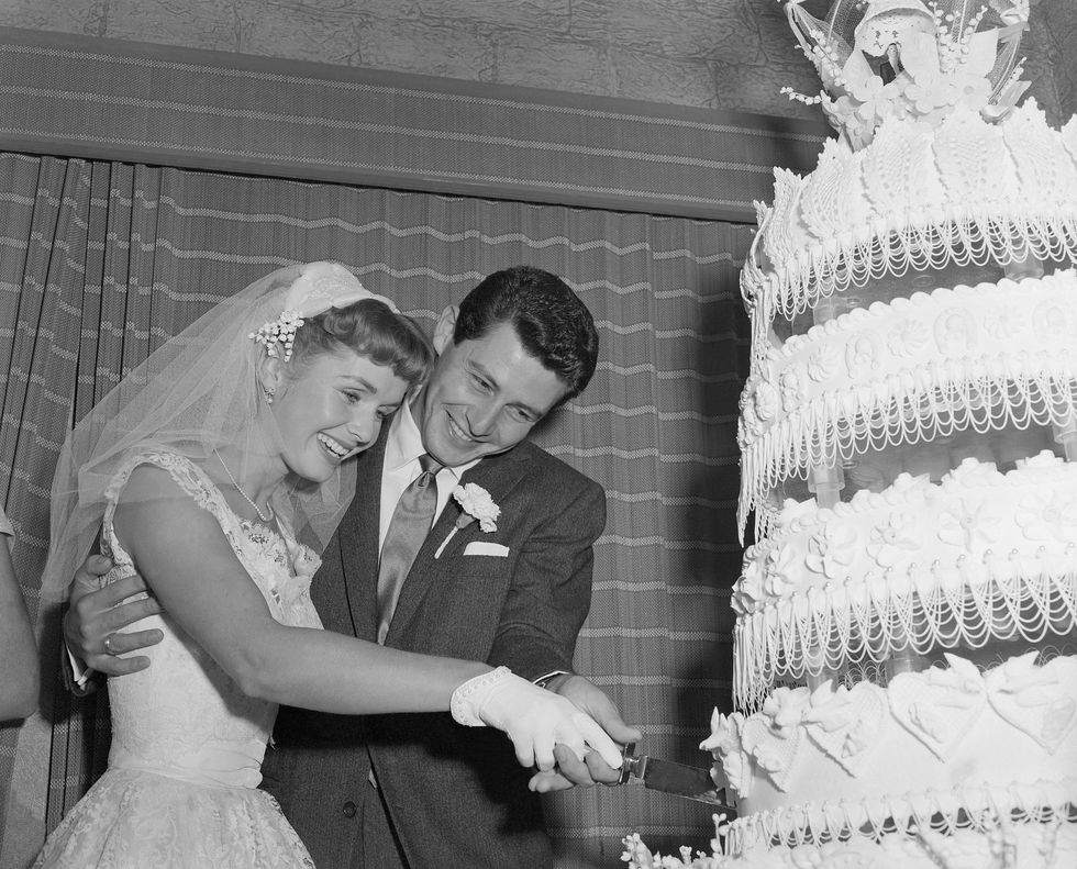 Debbie Reynolds and Eddie Fisher cutting their wedding cake