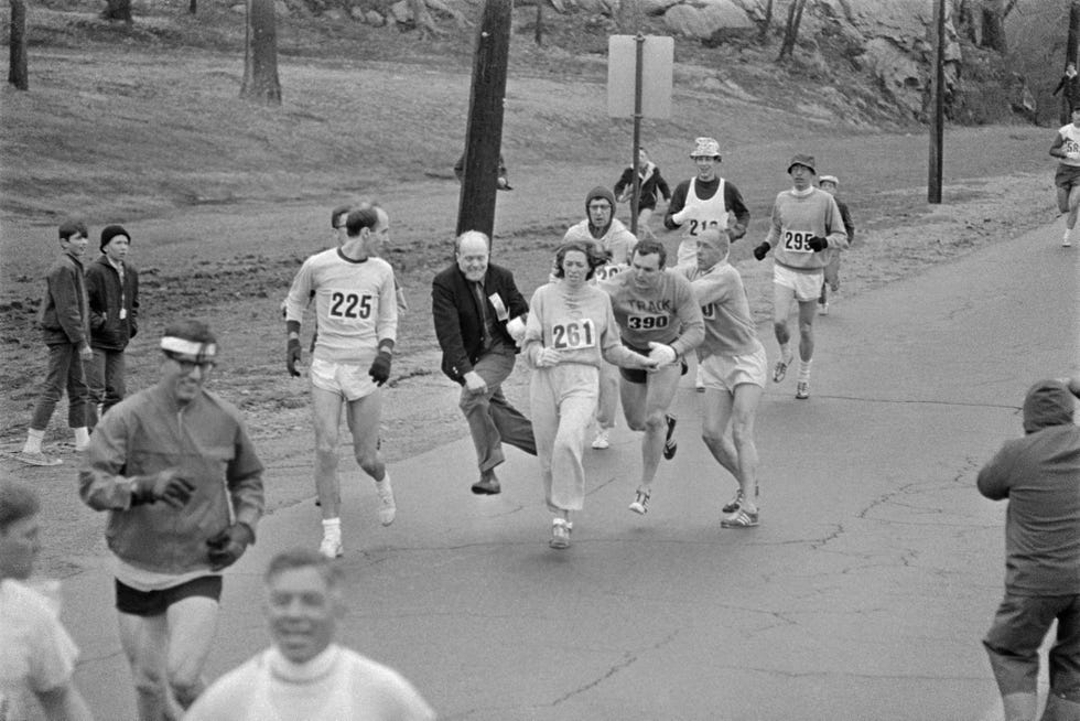 original caption in the boston marathon, one of two women running in the normally all male race, kathy switzer, 261 of syracuse, new york, is being hassled by baa marathon director bill cloney, as he attempted to stop her from competing the dark haired girl did not show up for the physical examination required of all starters, had she appeared at the starting line, she would never have been allowed to compete she remained in the race, but was never seen near the finish line