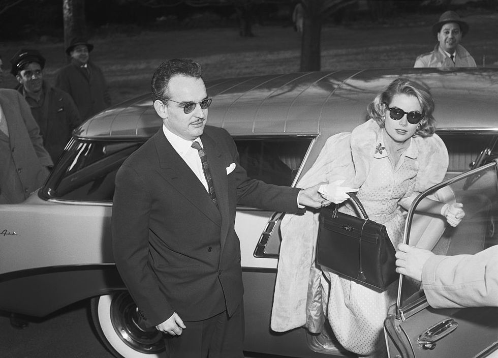 prince rainier iii of monaco helping his fiancee grace kelly out of a car kelly holds the style of hermes handbag that was named after her