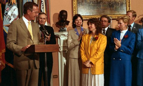 Christa McAuliffe smiles as George Bush announces that she will be the first non-astronaut to fly in space on July 19, 1985 in Washington, D.C.