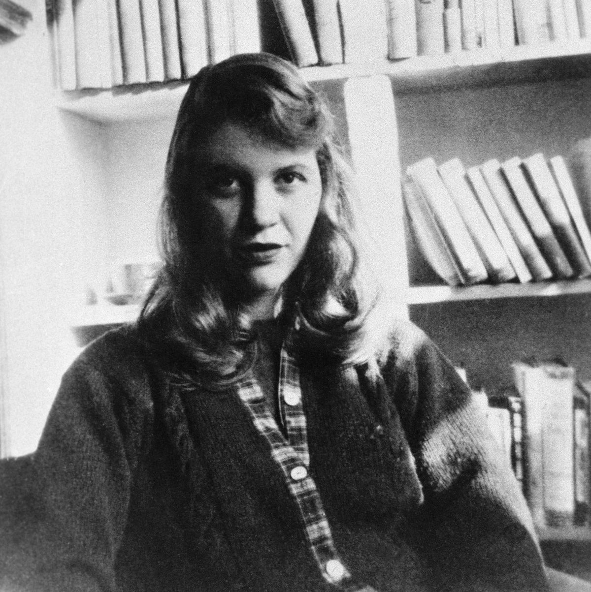 original caption photo shows author sylvia plath seated in front of a bookshelf