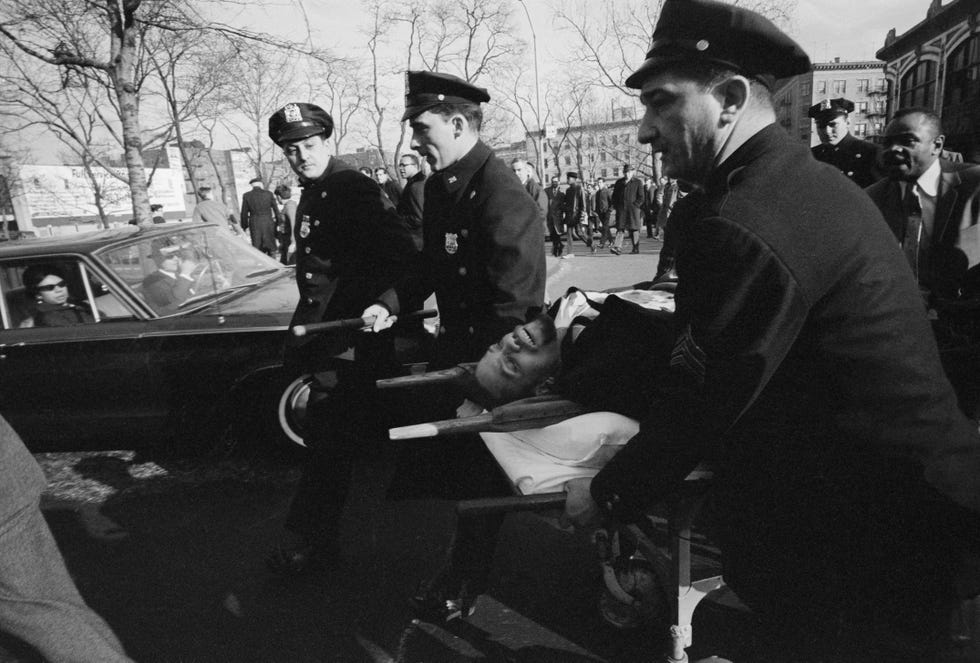 Police officers remove the body of Malcolm X from the Audubon Ballroom after his fatal shooting just before a speech on February 21, 1965, in Harlem, New York