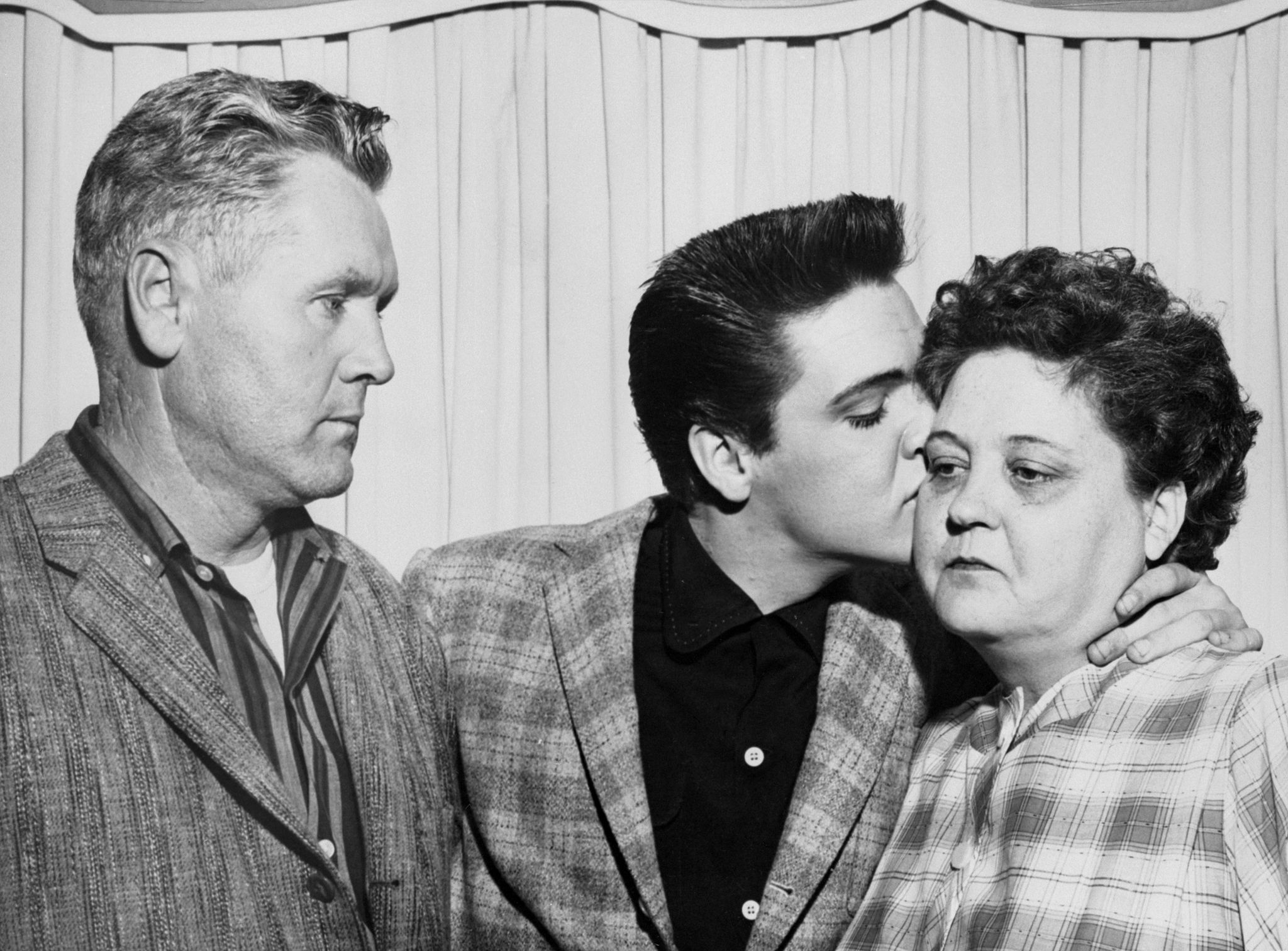 singer elvis presley kisses his mother, gladys, on the eve of his induction into the army at left is his father, vernon
