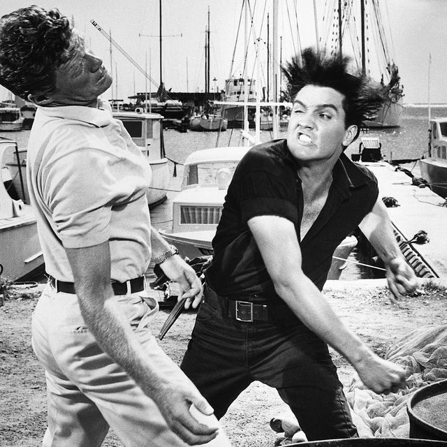 With his hair standing on end, and a nasty snarl, Elvis Presley proves he can belt a man just as much as he can belt a real tune. The mean blow clipped Jeremy Slate, in a scene from Hal Wallis's "Girls! Girls! Girls!", a musical from Paramount. Presley, the singing hero in the fil, takes apart Slate for trying to steal his girl, Laurel Goodwin.