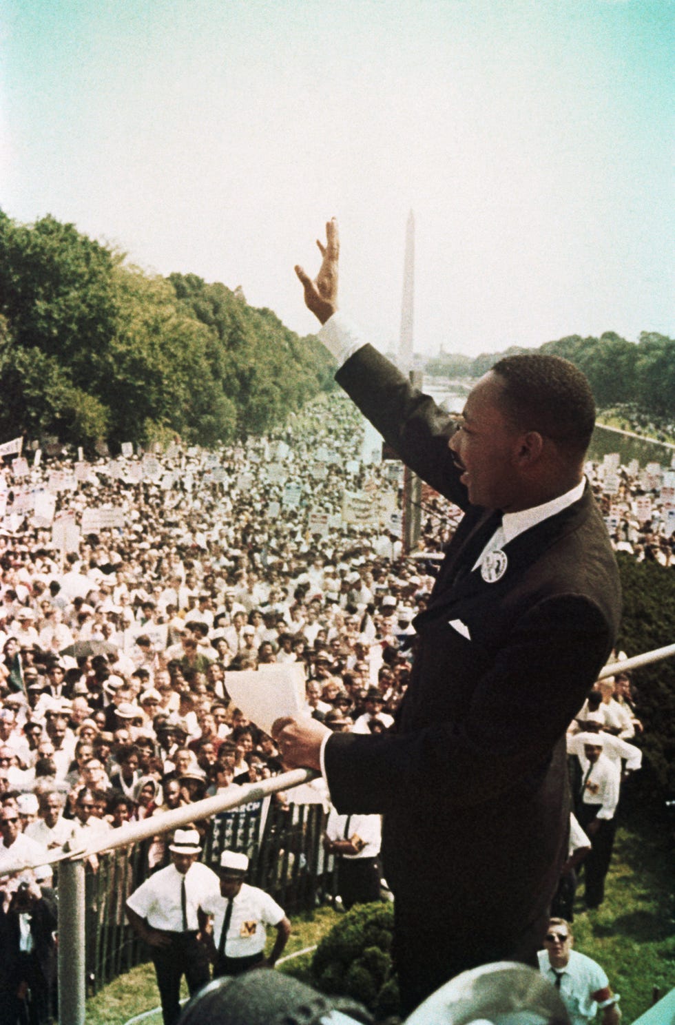 martin luther king jr waves to a gigantic crowd as the washington monument sits in the background