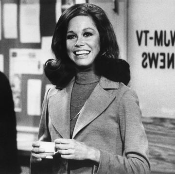 original caption still from the mary tyler moore show showing moore standing, smiling, inside of the wjm newsroom moore is shown from the waist up, holding a cup of coffee, circa 1975
