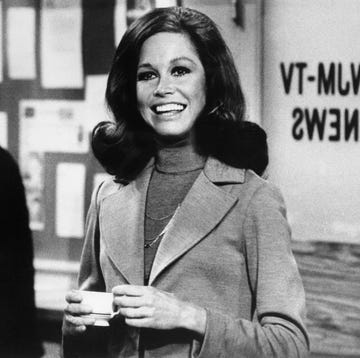 original caption still from the mary tyler moore show showing moore standing, smiling, inside of the wjm newsroom moore is shown from the waist up, holding a cup of coffee, circa 1975