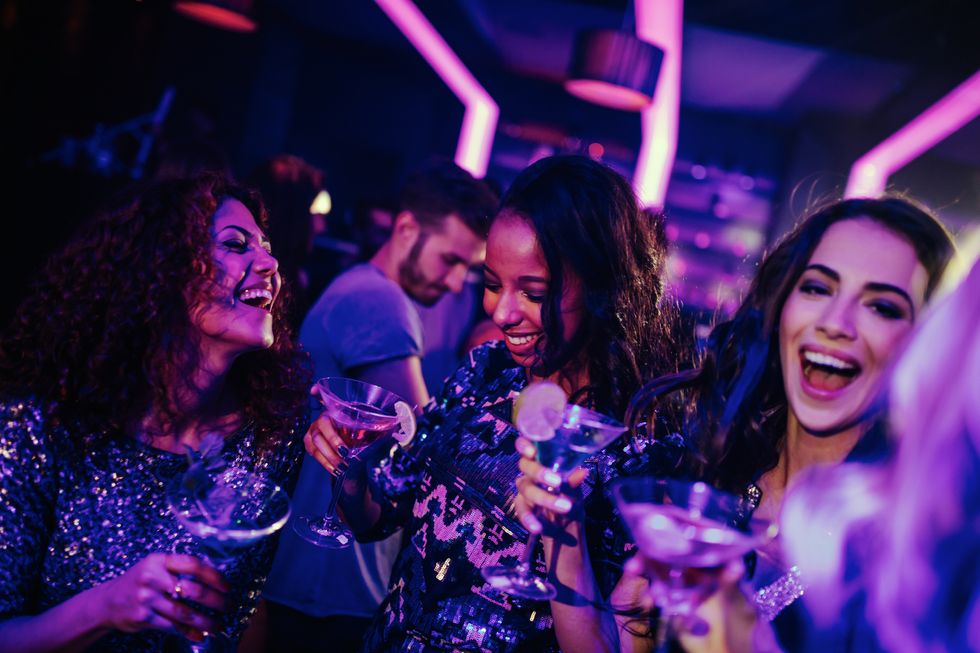 group of multi ethnic girls having fun on a night club party with some drinks
