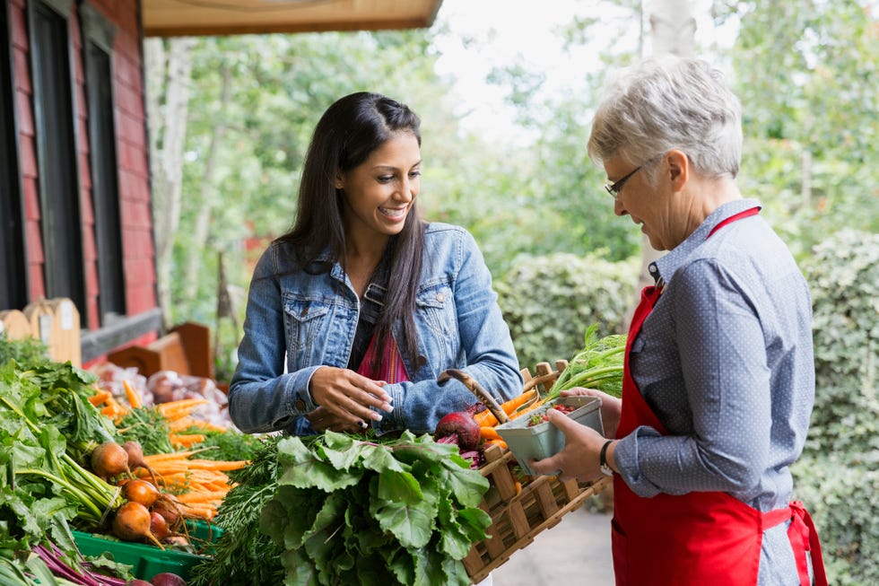 Worker helping woman with produce outside market