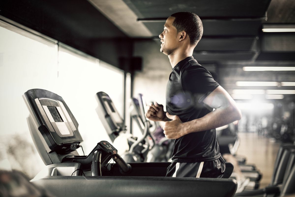 healthy young man in gym running on treadmill
