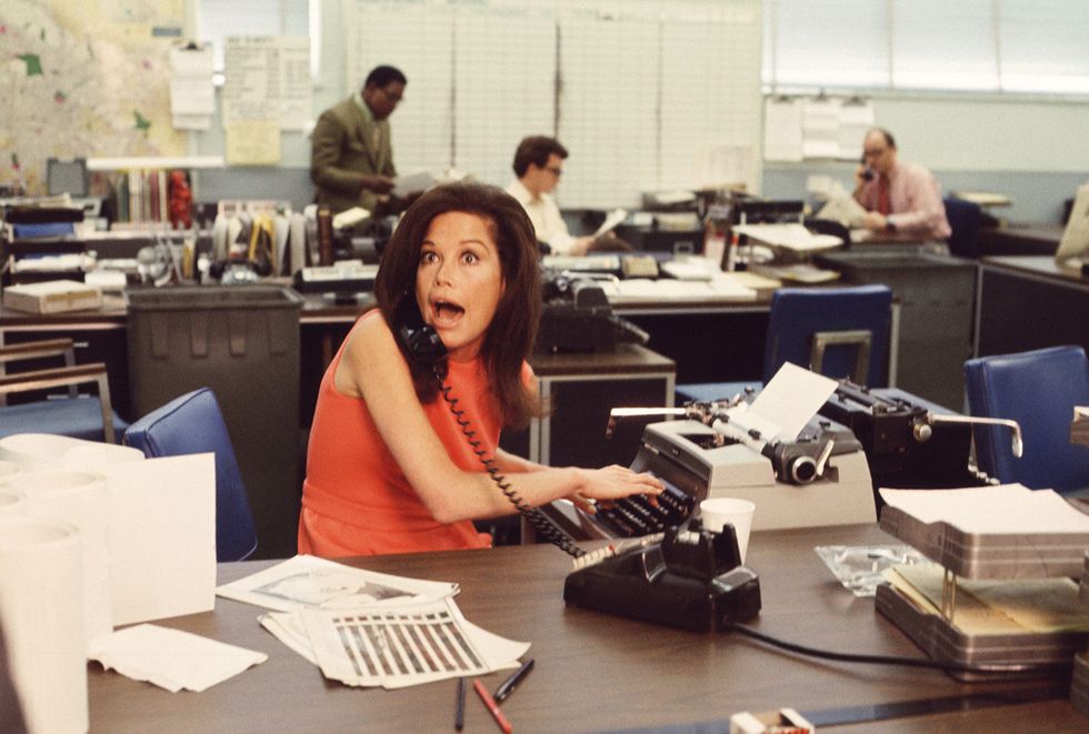 american actress mary tyler moore mouths surprise on the telephone while simultaneously typing as others work in the background in a scene from the mary tyler moore show also known as mary tyler moore, los angeles, california, early 1970s moore wears a sleevless orange dress as she sits behind her desk photo by cbs photo archivegetty images