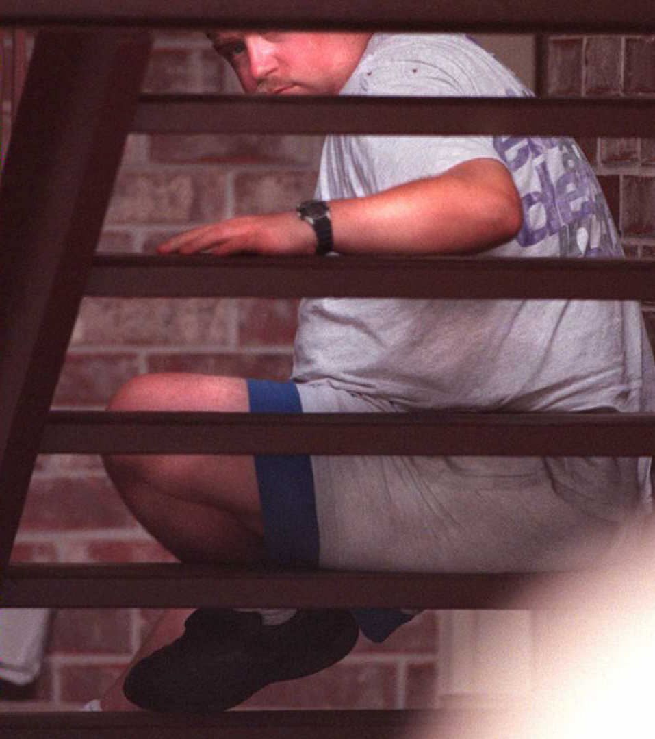 Richard Jewell looks through stairs at his apartment complex while FBI and local police agents search his apartment on July 31, 1996