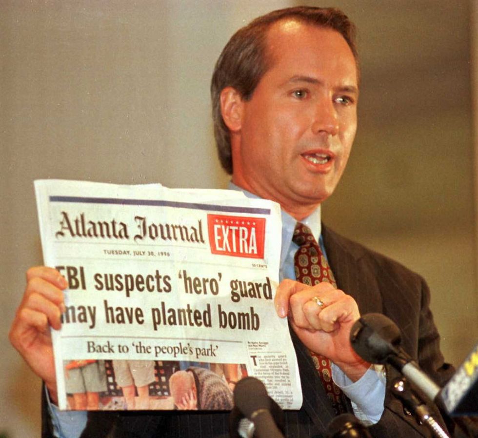 Richard Jewell's attorney Lin Wood holds a copy of the Atlanta Journal during a press conference on October 28, 1996, in Atlanta, Georgia