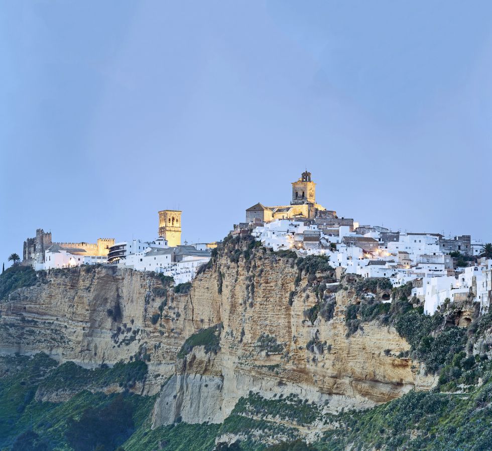 arcos de la frontera, cadiz province, andalucia, spain, europe view of the old town perched on the hilltop dominated by the castillo de los duques centred and the basilica parroquia de santa maria on the left