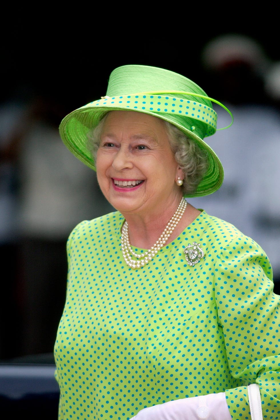 montego bay, jamaica february 20: queen elizabeth ll laughing whilst attending the governor generals garden fair at the half moon hotel to see jamaican produce and listen to jamaican music. the queen is wearing a lime green dress with blue polka dots and a geen hat trimmed with material to match the dress. she has chosen to wear a pearl necklace, pearl earrings and a diamond brooch with this outfit. she is wearing a hat by philip somerville. (photo by tim graham photo library via getty images)