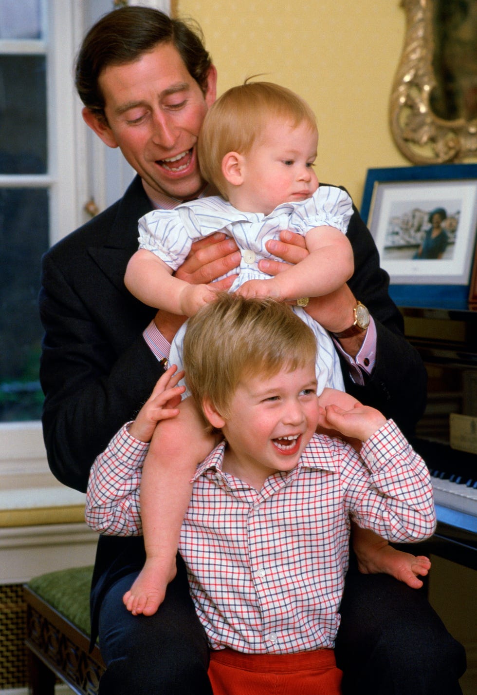 prince charles laughing with his sons as he lifts prince harry onto prince williams shoulders in kensington palace