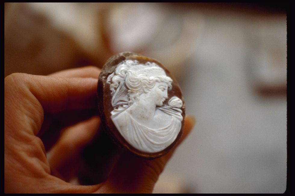a cameo maker holds an almost finished cameo at a cameo factory in pompeii, italy