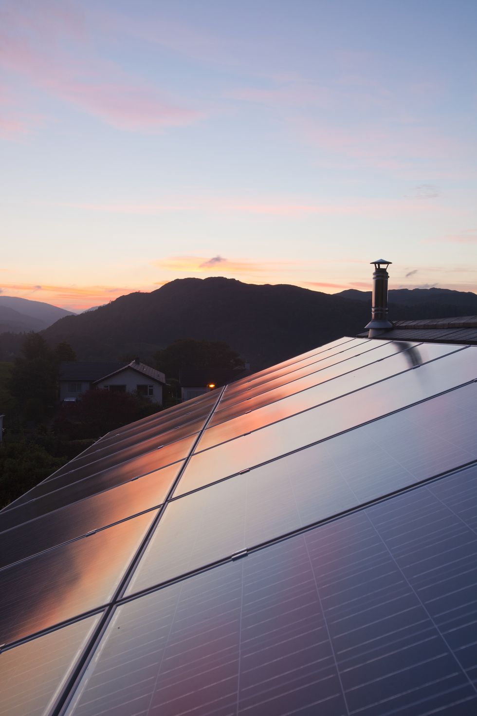 sunset over a house in ambleside, lake district uk, with a 38 kw solar electric panel system on the roof