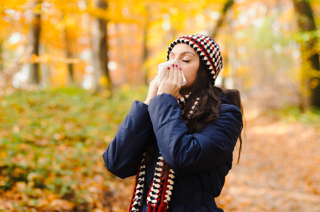 Woman sneezing in handkerchief at autumn