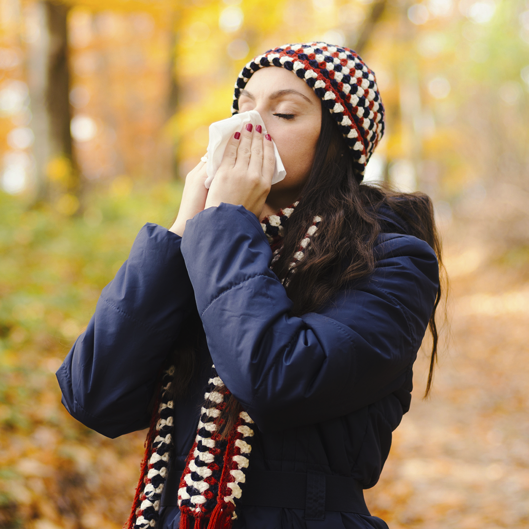 Woman sneezing in handkerchief at autumn