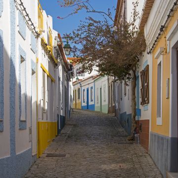 empty cobblestone street with colorful houses in ferragudo, algarve region of portugal