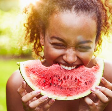 portrait of a young woman eating watermelon on a sunny day, backlit a boy eating a watermelon