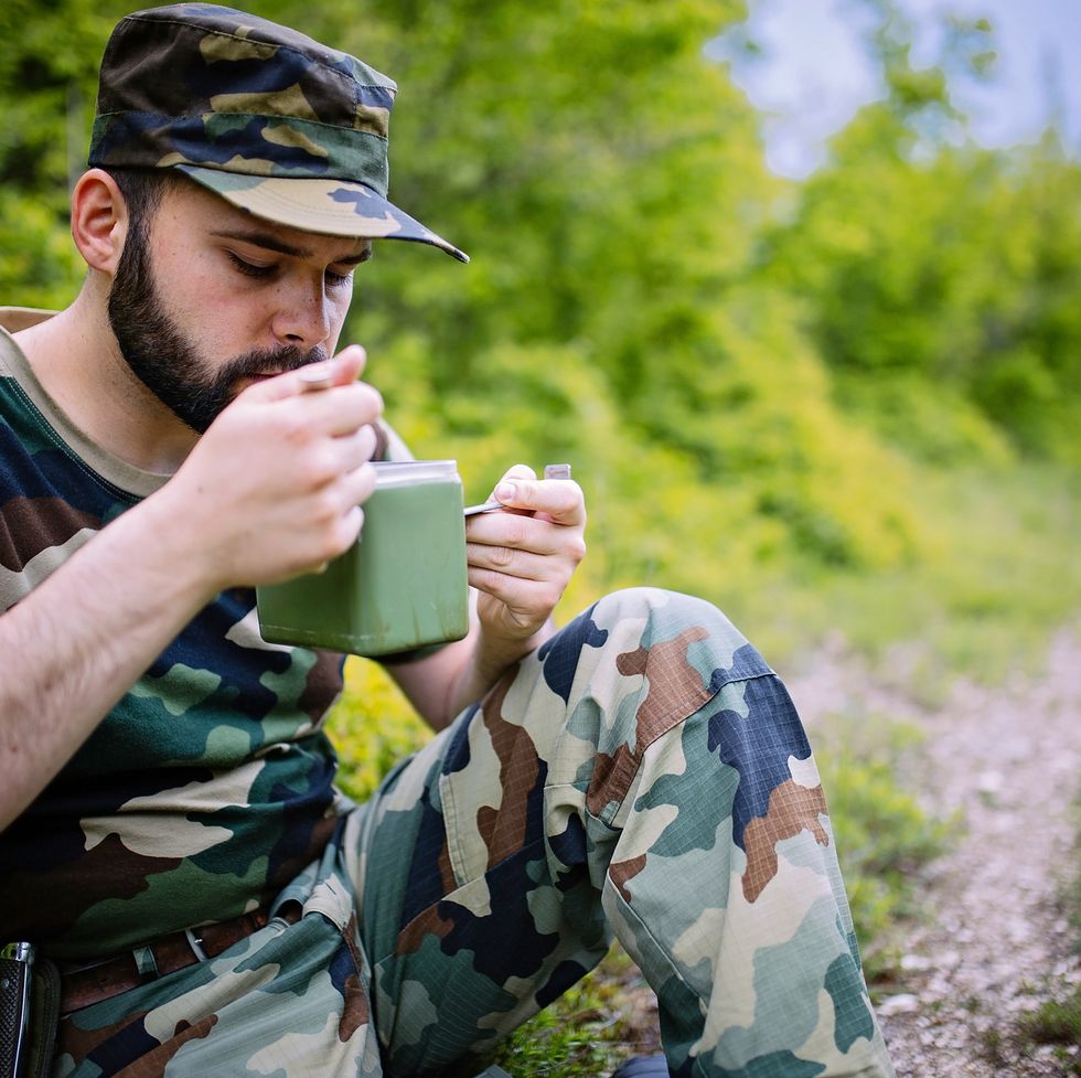 soldier taking a break, he is eating his meal in the wild  military diet