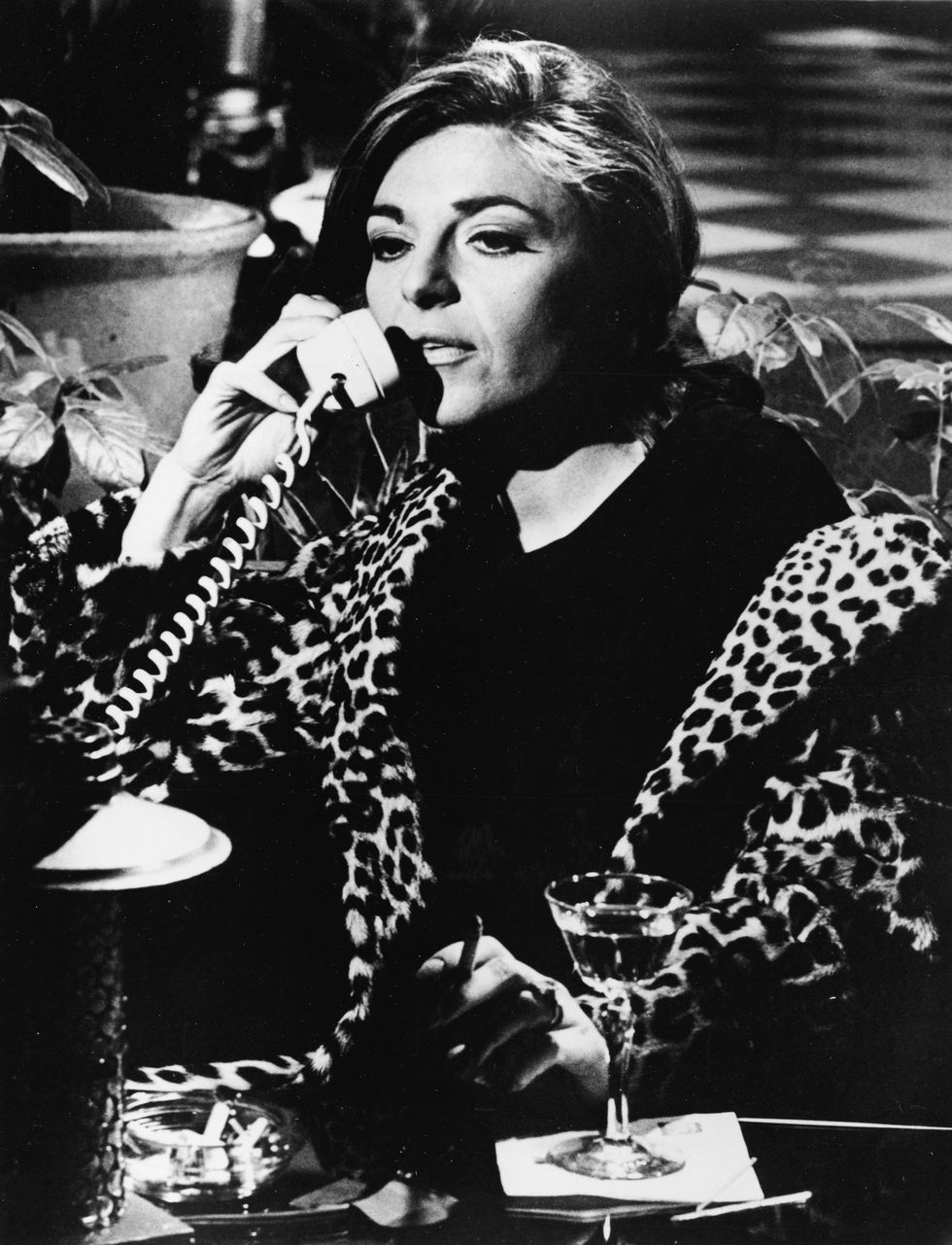 american actress anne bancroft 1931 2005 wears a leopard print coat as she talks on the phone, drinks, and smokes in character as the seductive older woman, mrs robinson, in a still from the film the graduate directed by mike nichols, california, 1967 photo by embassy picturesmgm studioscourtesy of getty images