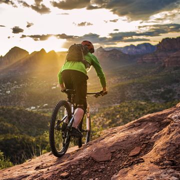 a male mountain biker rides the famous hangover trail above sedona, arizona as the late afternoon sun shines through sedona is famous for its slickrock trails, with this trail being one of its more iconic routes