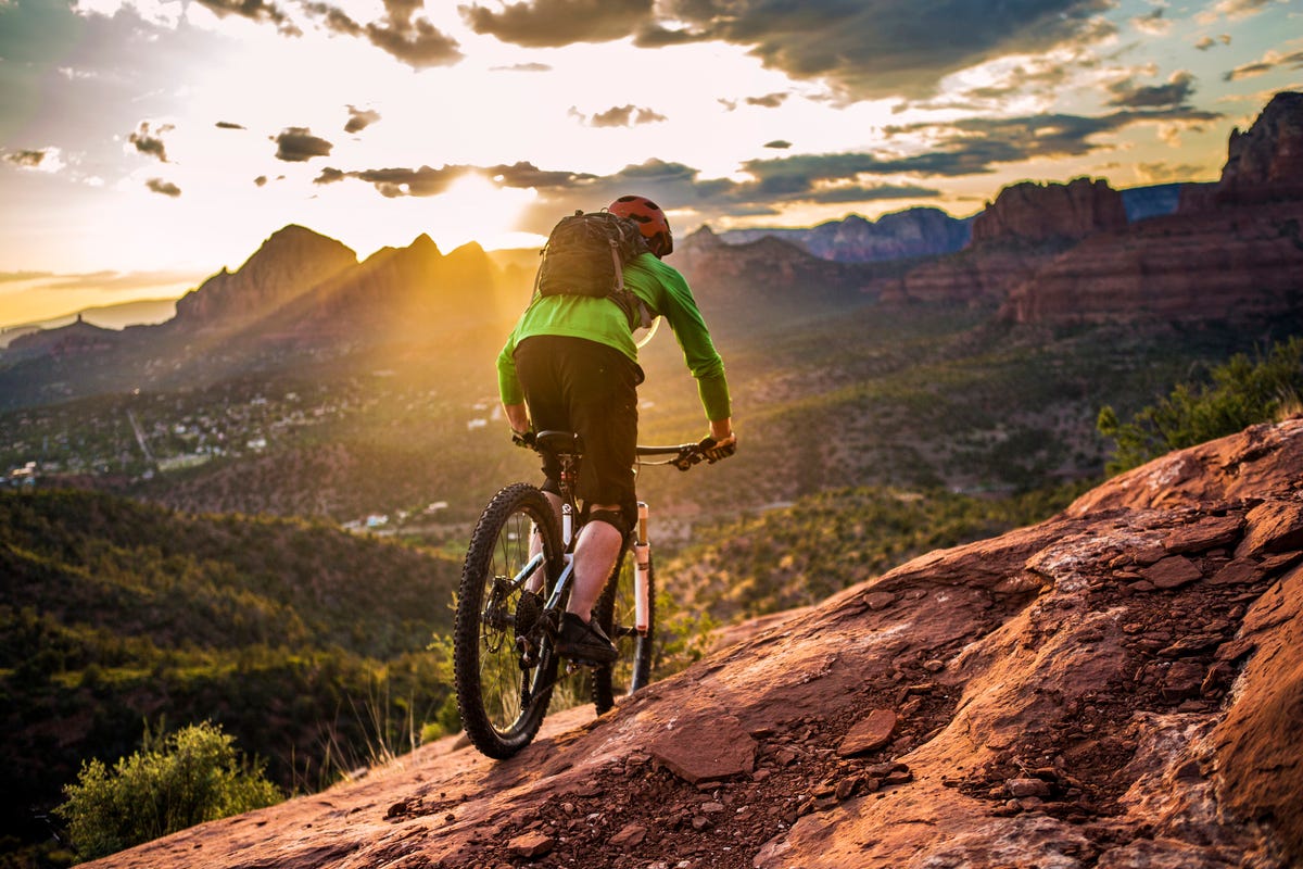 a male mountain biker rides the famous hangover trail above sedona, arizona as the late afternoon sun shines through sedona is famous for its slickrock trails, with this trail being one of its more iconic routes