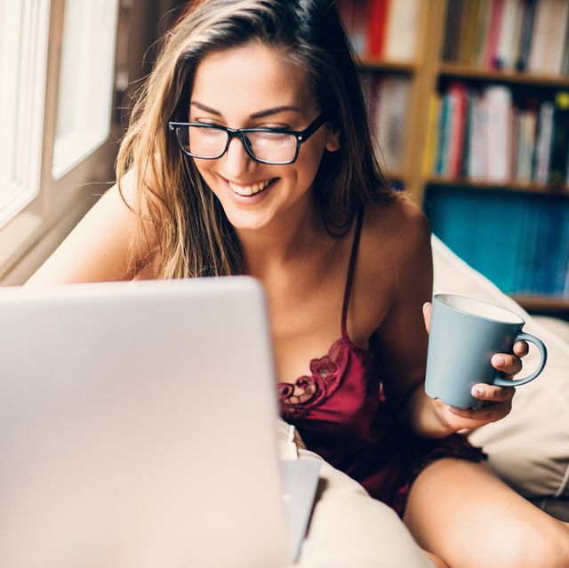 woman dressed in a sexy lingerie drinking coffee and using a laptop
