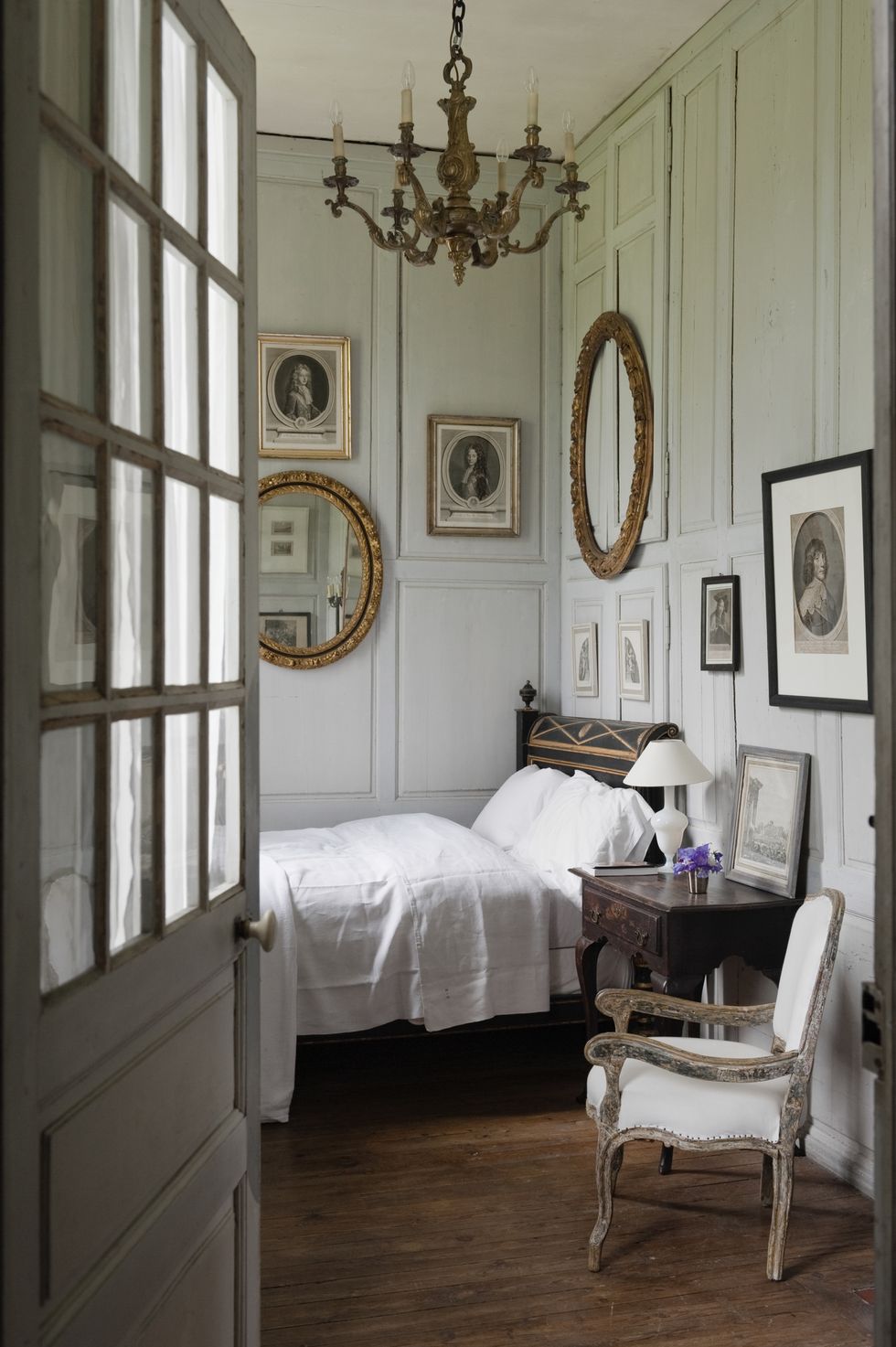 view through open doorway to charming bedroom with wooden wall panelling and french antiques