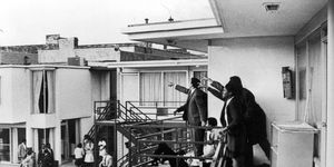 Andrew Young and others standing on balcony of Lorraine Motel pointing in direction of assailant after assassination of civil rights leader Martin Luther King Jr., who is lying at their feet.
