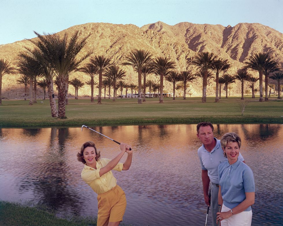 Golfer swinging in front of pond with Joan Bohanno