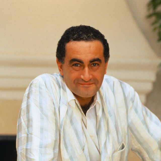 dodi fayed smiles at the camera and wears a blue, white and cream plaid jacket over a white collared shirt