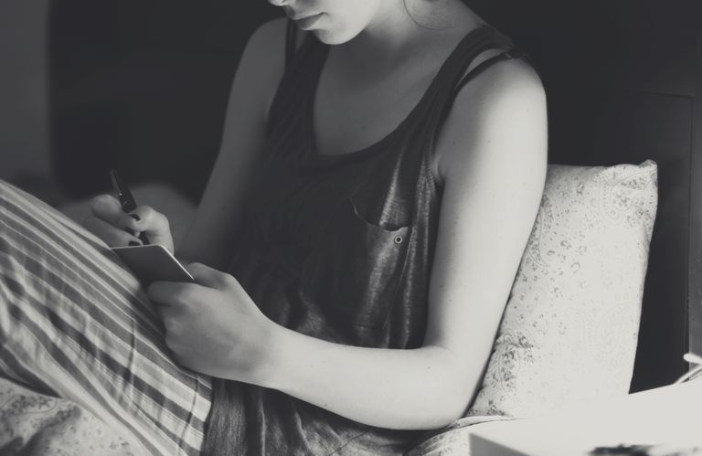 Young woman writing diary in bed