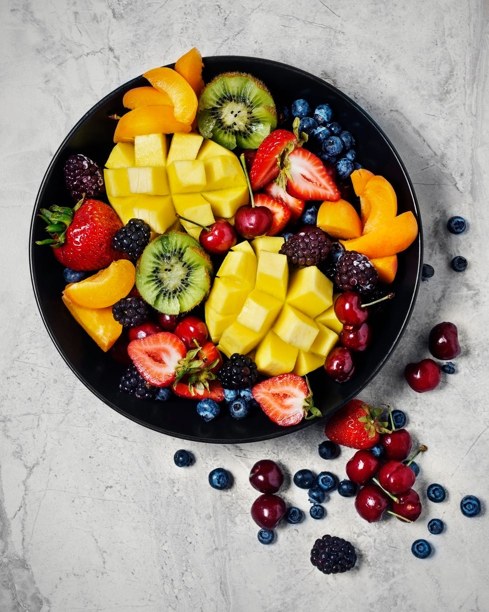 variety of fresh fruit in a bowl on stone background