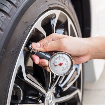 close up of hand holding pressure gauge for car tyre pressure measurement