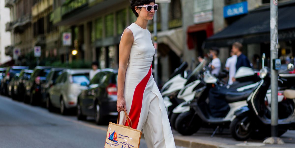 a person in a white dress carrying a bag on a street