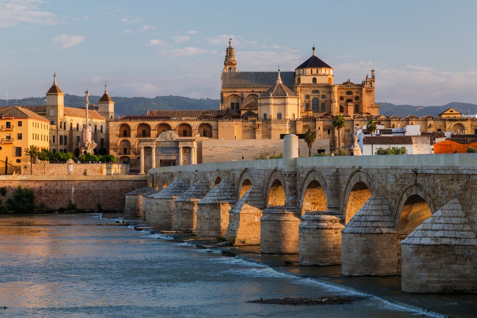"arches of urban bridge in cordoba cityscape, andalusia, spain"