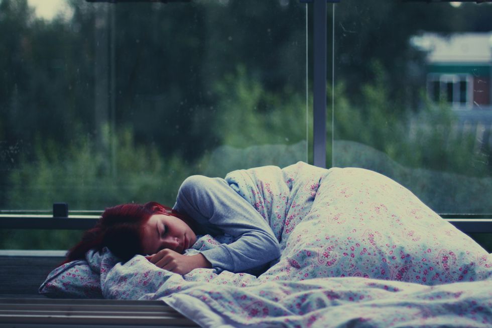 Young woman sleeping at bus shelter