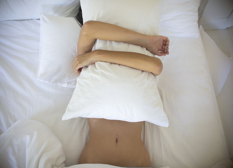 Woman in bed with pillow over face