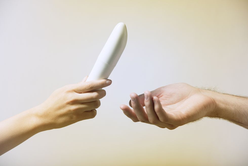 close up of womans hand, handing a mans hand a vibrator