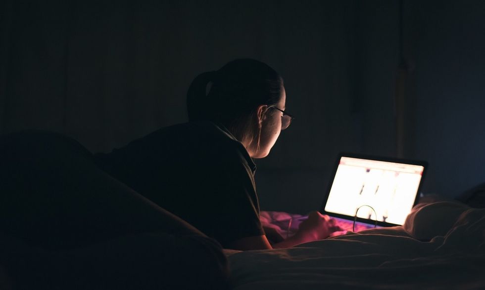 Rear View Of Woman Using Laptop On Bed