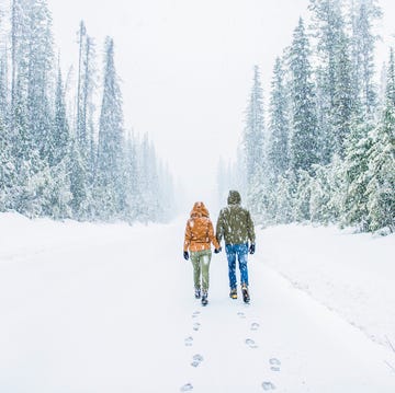 Caucasian couple walking on snowy forest road pareja andando bajo la nieve