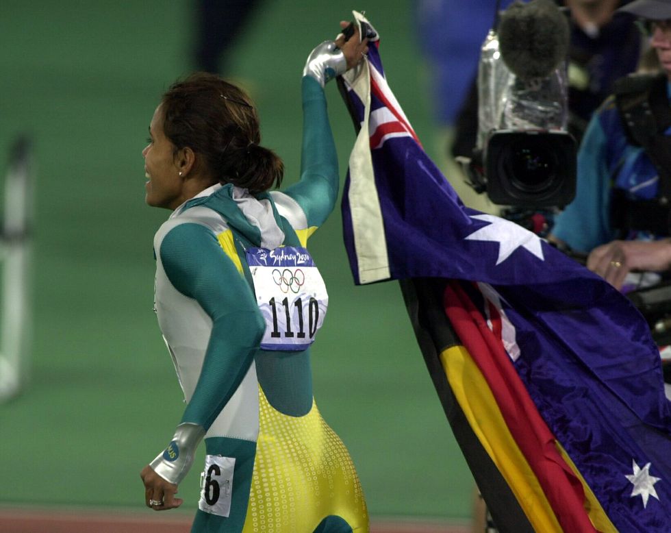 sydney, australia   september 25  cathy freeman sets off on a lap of honour carrying the australian and aboriginal flags the olympic stadium, sydney, monday, after her win in the womens 400m finalin a time of 4911sec  photo by ross landgetty images